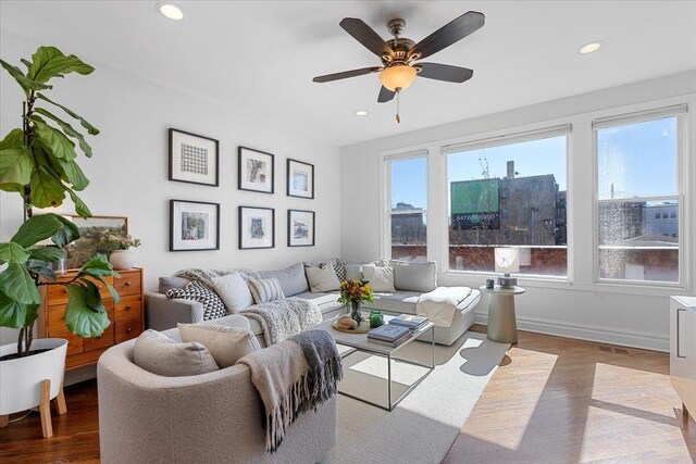 living area with a view of city, recessed lighting, a ceiling fan, wood finished floors, and baseboards