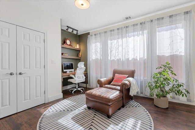 interior space featuring baseboards, visible vents, built in study area, wood finished floors, and track lighting