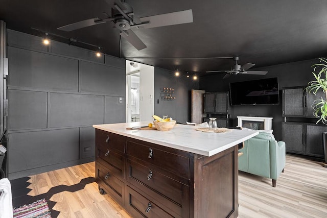 kitchen featuring light wood-style flooring, a kitchen island, light countertops, and a ceiling fan