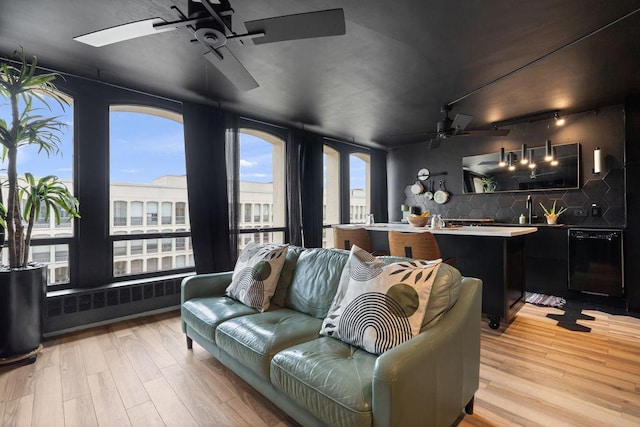 living area with light wood-type flooring, radiator, and ceiling fan