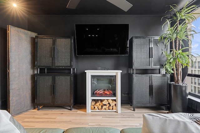 living room with a warm lit fireplace and wood finished floors