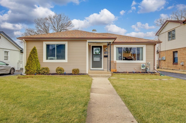 bungalow with a shingled roof and a front yard