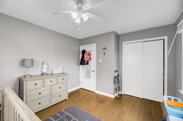 bedroom with a closet, wood finished floors, a ceiling fan, and baseboards