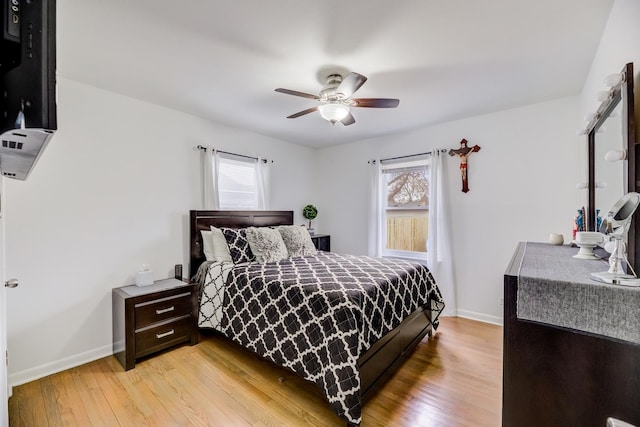 bedroom featuring light wood-type flooring, multiple windows, and baseboards