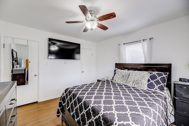 bedroom featuring a ceiling fan, light wood-style flooring, and baseboards