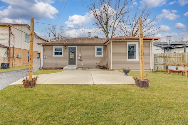 back of house featuring a patio, a lawn, fence, and driveway