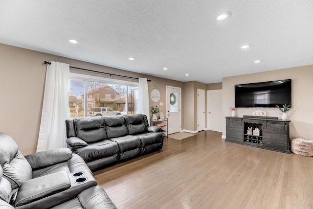 living area featuring baseboards, wood finished floors, a textured ceiling, a fireplace, and recessed lighting