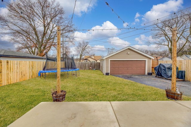 view of yard with an outbuilding, a trampoline, a detached garage, and a fenced backyard