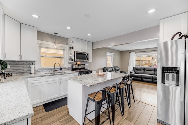 kitchen with appliances with stainless steel finishes, a sink, white cabinetry, and tasteful backsplash