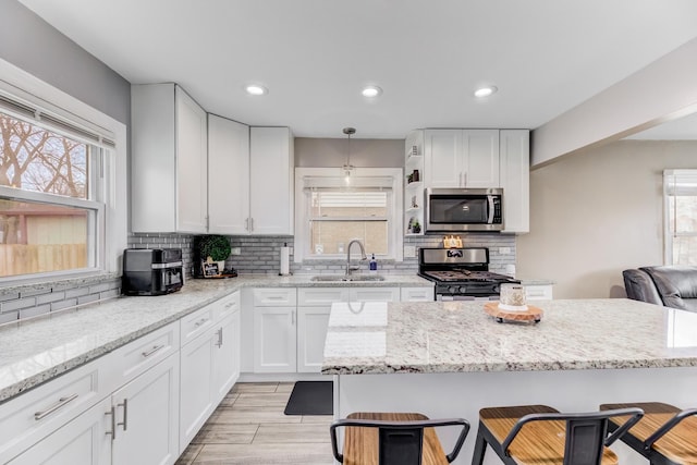 kitchen featuring stainless steel appliances, a wealth of natural light, a sink, and a kitchen bar