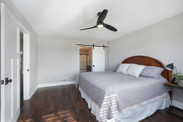 bedroom with visible vents, baseboards, a barn door, and wood finished floors