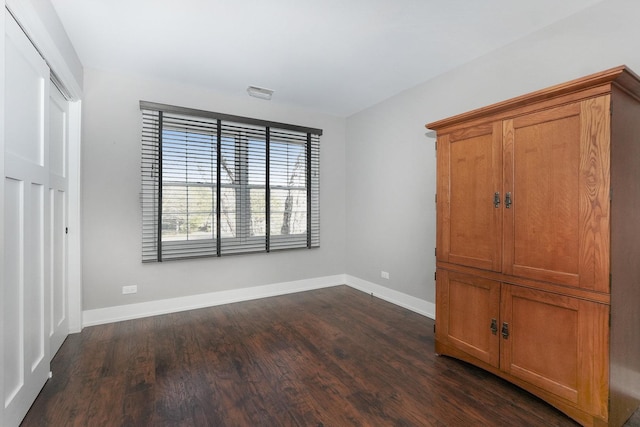 unfurnished bedroom with dark wood-style floors, visible vents, and baseboards