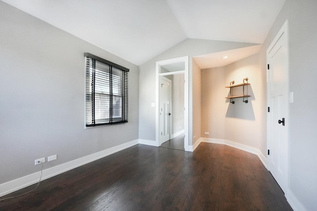 unfurnished room featuring lofted ceiling, baseboards, and dark wood-type flooring