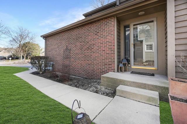 property entrance featuring a yard and brick siding