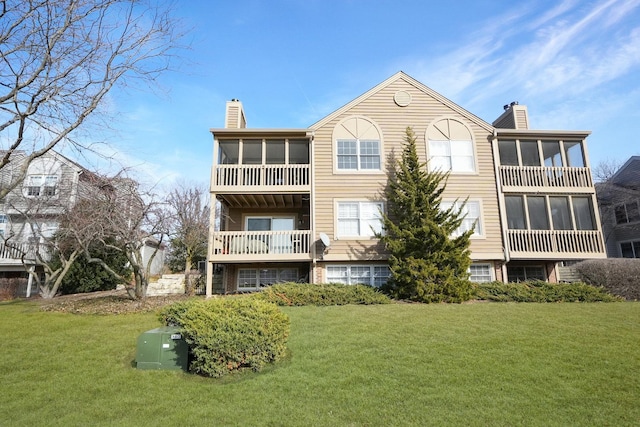 rear view of property with a yard, a chimney, and a sunroom