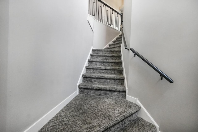 staircase featuring baseboards and carpet floors