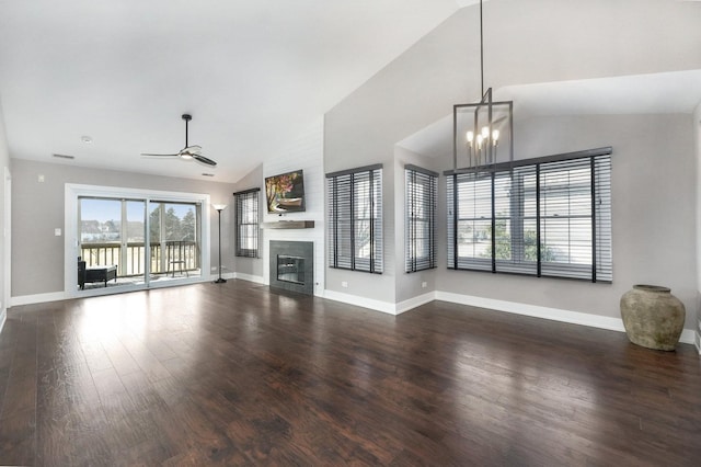 unfurnished living room with wood finished floors, baseboards, high vaulted ceiling, a glass covered fireplace, and ceiling fan with notable chandelier