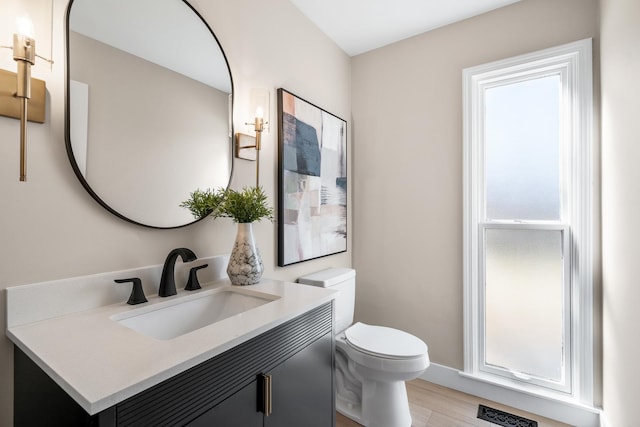 bathroom featuring toilet, wood finished floors, visible vents, vanity, and baseboards