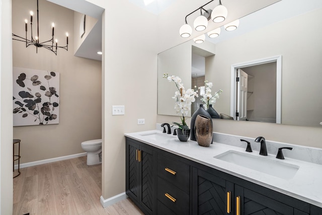 bathroom with toilet, baseboards, a sink, and wood finished floors