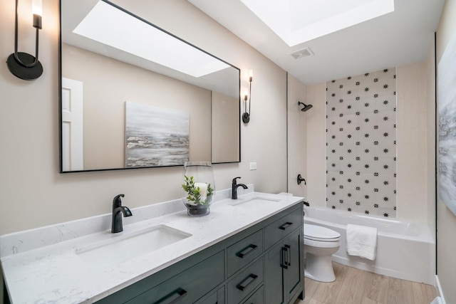 full bath featuring a skylight, tub / shower combination, a sink, and toilet