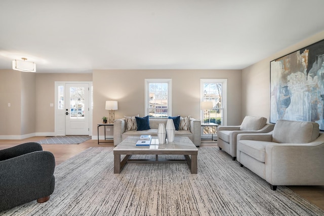 living area featuring baseboards, light wood-type flooring, and a healthy amount of sunlight