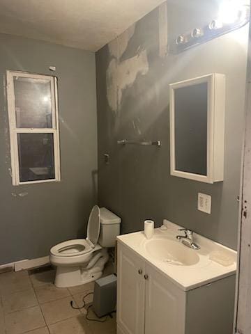 bathroom with toilet, vanity, and tile patterned floors