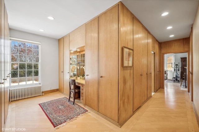 hall with light wood-type flooring, radiator heating unit, baseboards, and recessed lighting