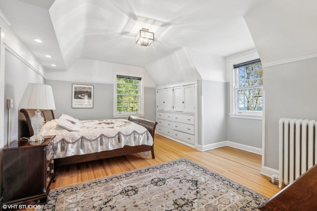 bedroom featuring radiator heating unit, light wood-type flooring, multiple windows, and lofted ceiling