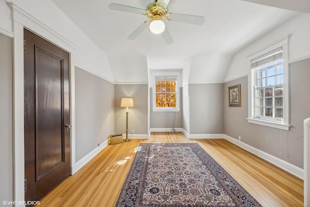 interior space featuring baseboards, light wood-type flooring, ceiling fan, and lofted ceiling