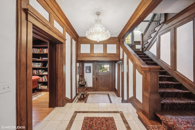 foyer entrance with an inviting chandelier, baseboards, and stairway