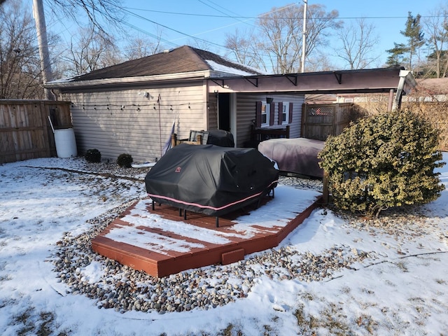 snow covered property with a carport and fence