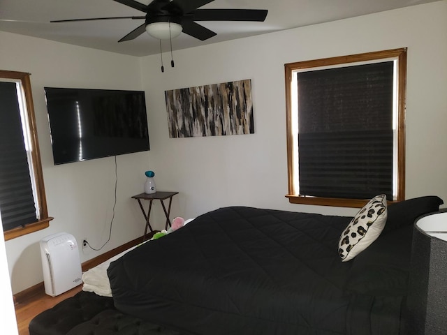 bedroom featuring wood finished floors, a ceiling fan, and baseboards