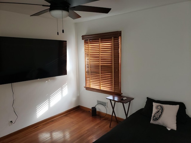 bedroom featuring a ceiling fan, visible vents, baseboards, and wood finished floors