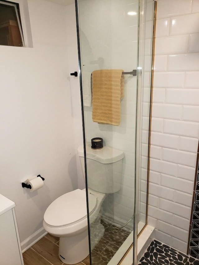 bathroom with baseboards, toilet, wood finished floors, vanity, and a shower stall