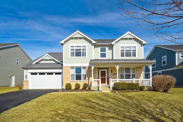 craftsman inspired home with driveway, covered porch, a front lawn, a garage, and brick siding