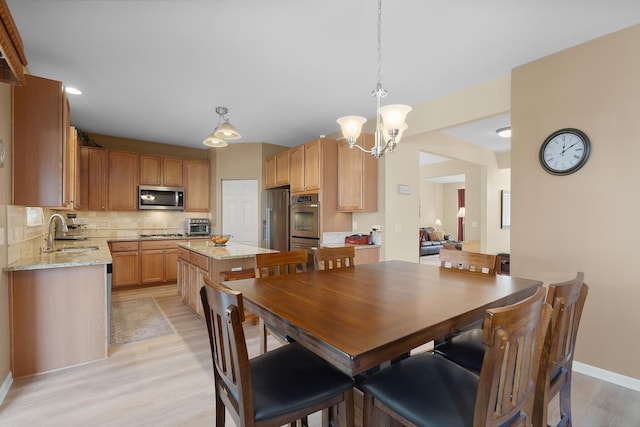 dining room featuring a notable chandelier, a toaster, baseboards, and light wood-style floors