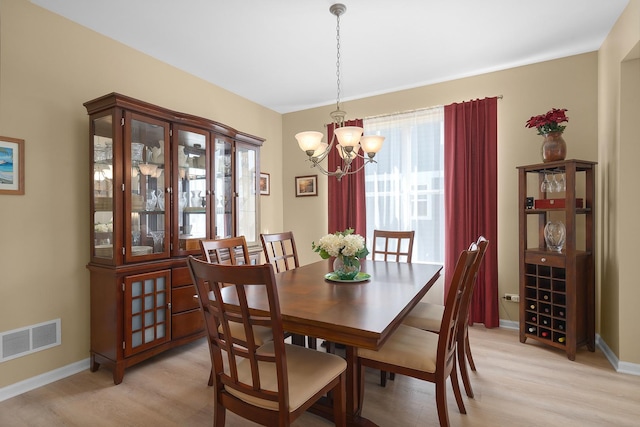 dining room with an inviting chandelier, baseboards, visible vents, and light wood finished floors