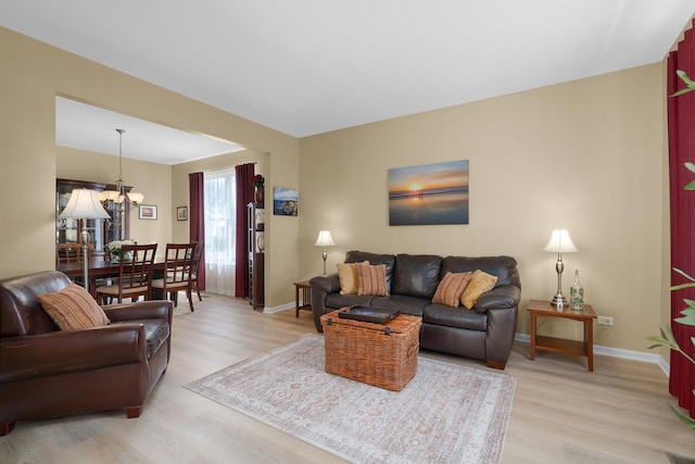 living area with a chandelier, baseboards, and light wood-style flooring