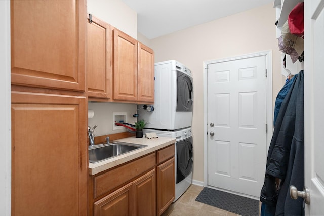 clothes washing area featuring stacked washing maching and dryer, cabinet space, and a sink