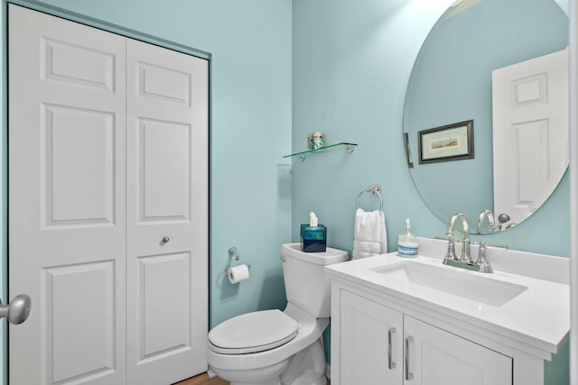 bathroom with a closet, toilet, and vanity