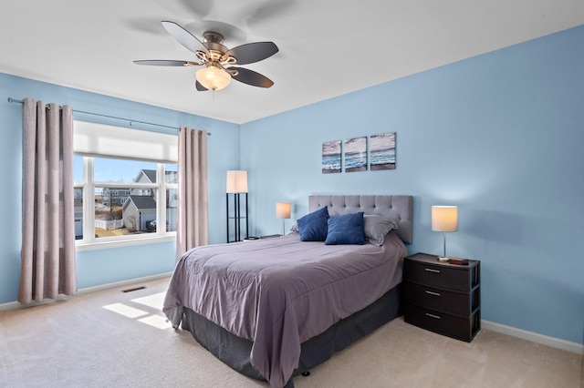 bedroom featuring visible vents, light colored carpet, a ceiling fan, and baseboards