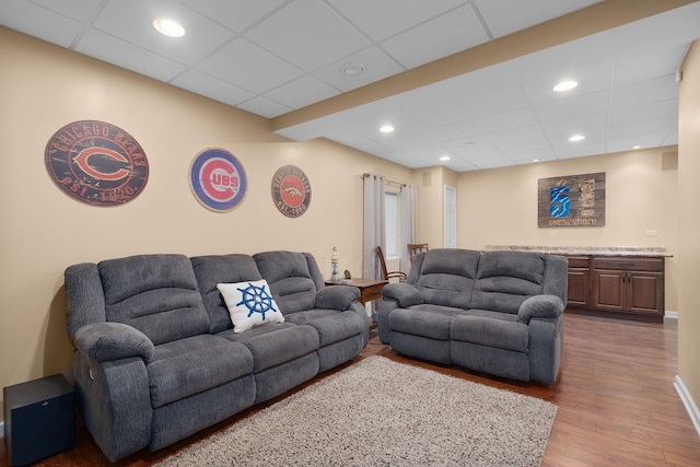 living room with recessed lighting, a paneled ceiling, and wood finished floors