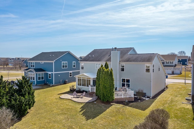 back of property with a residential view, a chimney, a patio, and a sunroom