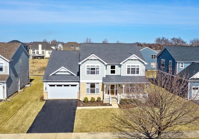 traditional home with a front lawn, aphalt driveway, a residential view, roof with shingles, and an attached garage