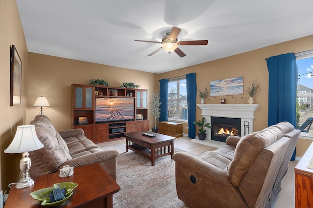 living room with a glass covered fireplace and ceiling fan