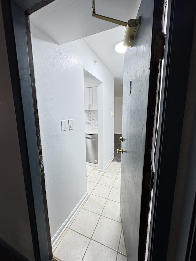 hall featuring light tile patterned flooring and baseboards