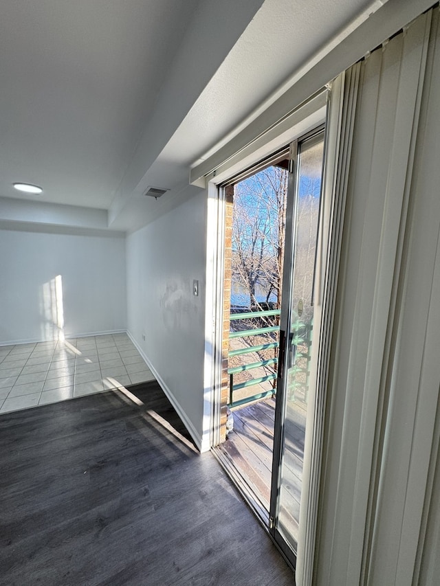 doorway with wood finished floors, visible vents, and baseboards