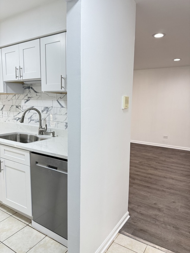 kitchen with white cabinets, dishwasher, backsplash, a sink, and light tile patterned flooring