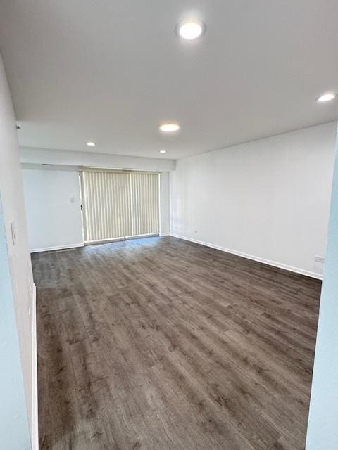 empty room with baseboards, wood finished floors, and recessed lighting