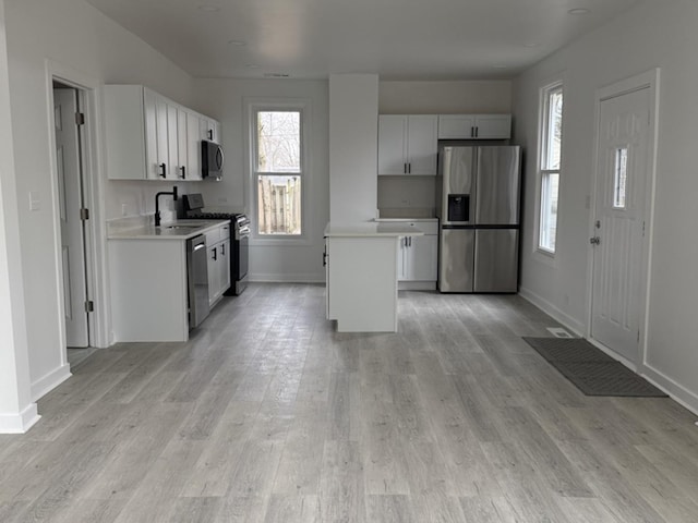 kitchen with light countertops, appliances with stainless steel finishes, light wood-type flooring, and a sink